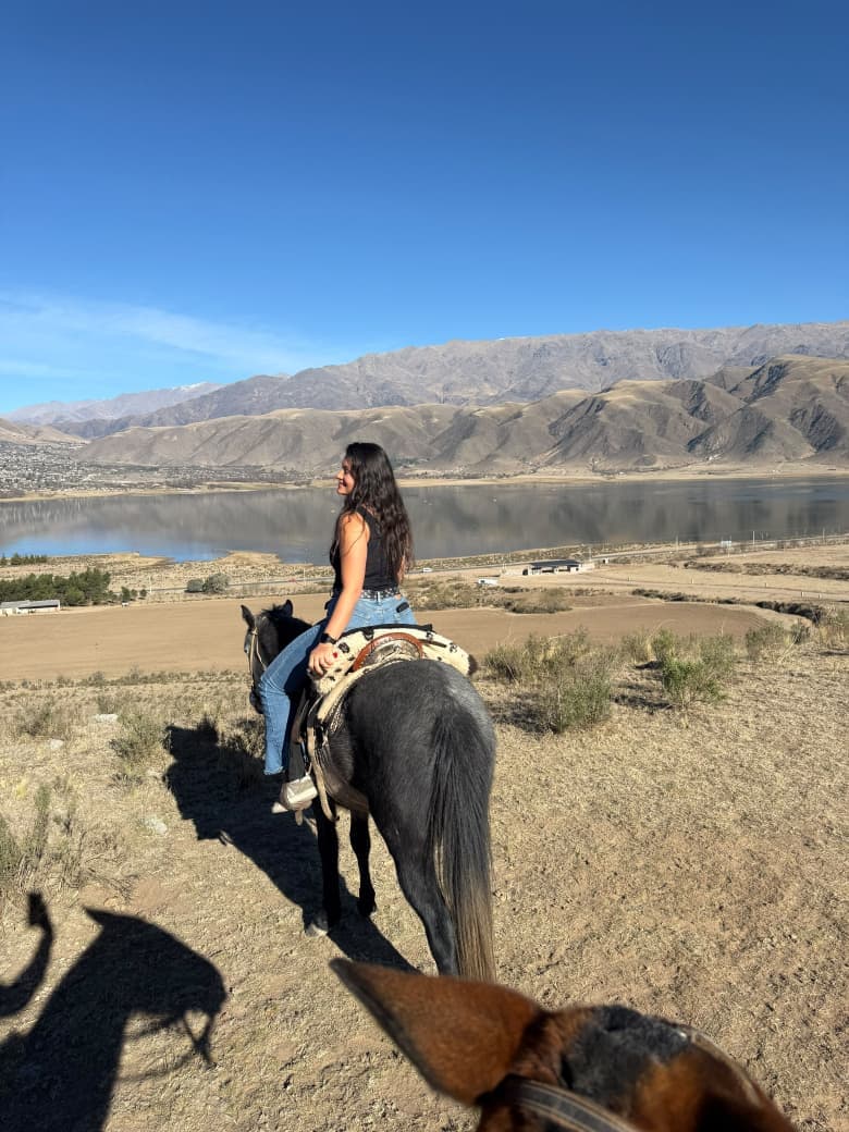 Jinete recorriendo a caballo la orilla del Dique La Angostura, excursión Urku Wasi
